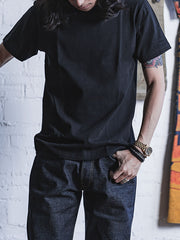 モデルがライトブルーのデニムジーンズと白いキャンバスシューズを合わせたヘビーウェイト半袖Tシャツを着用。カジュアルで個性的な日常のスタイルを展示している。