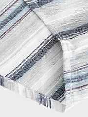 「シャツ裾のワインレッドの刺繍タグのクローズアップ。繊細さとおしゃれさを演出。」