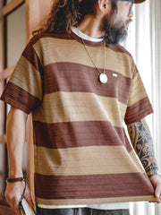 モデルがカラーブロック3Dストライプニット短袖Tシャツを着用し、シンプルなカジュアルパンツと白スニーカーでコーディネート。リラックスした夏の雰囲気を演出する洗練されたカジュアルスタイル。