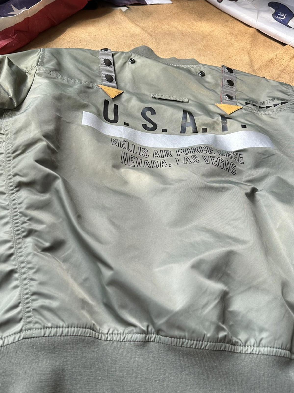 製品画像:57飛行隊機能性MA-1フライトジャケットの正面展示。取り外し可能なフード付きのミリタリー風ジャケット。
詳細画像:取り外し可能なフードと多機能ポケットのディテール。収納力と実用性を兼ね備えたデザイン。