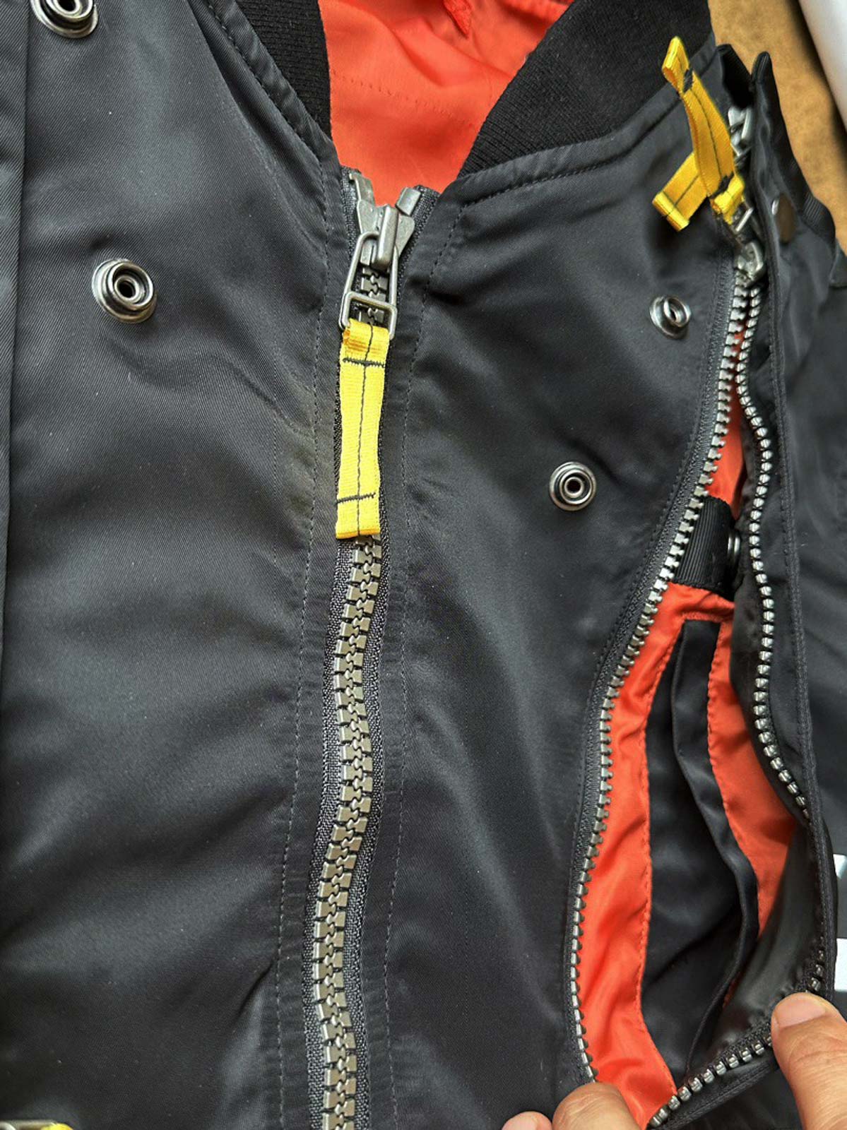 製品画像:57飛行隊機能性MA-1フライトジャケットの正面展示。取り外し可能なフード付きのミリタリー風ジャケット。
詳細画像:取り外し可能なフードと多機能ポケットのディテール。収納力と実用性を兼ね備えたデザイン。