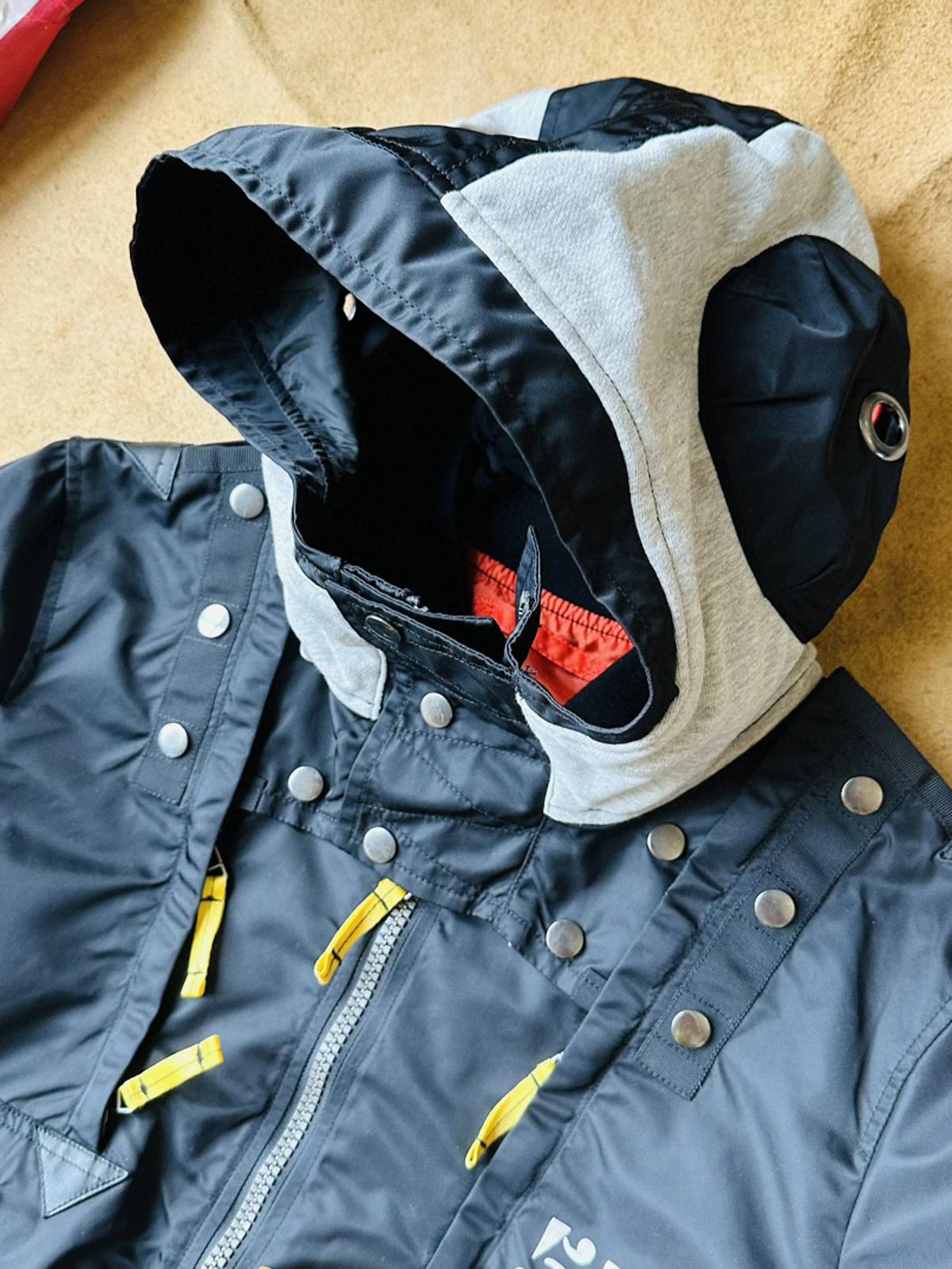 製品画像:57飛行隊機能性MA-1フライトジャケットの正面展示。取り外し可能なフード付きのミリタリー風ジャケット。
詳細画像:取り外し可能なフードと多機能ポケットのディテール。収納力と実用性を兼ね備えたデザイン。