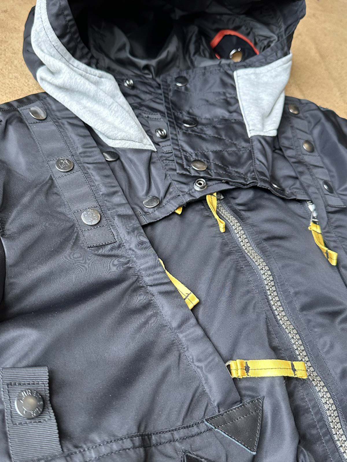 製品画像:57飛行隊機能性MA-1フライトジャケットの正面展示。取り外し可能なフード付きのミリタリー風ジャケット。
詳細画像:取り外し可能なフードと多機能ポケットのディテール。収納力と実用性を兼ね備えたデザイン。