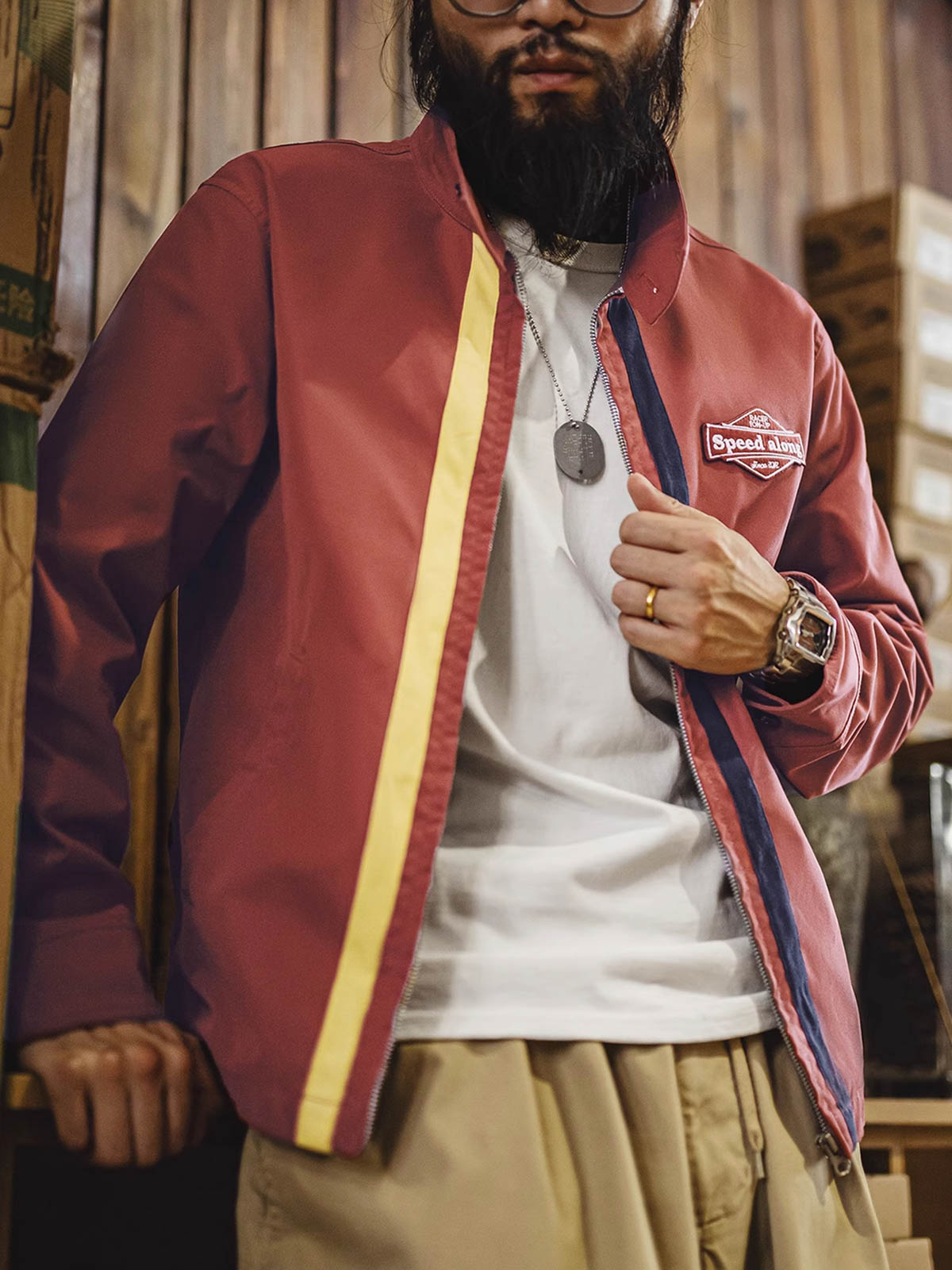 詳細画像: バイカラーのジッパーディテール、ツイル素材の高い耐摩耗性とレトロな赤色の特徴が分かる部分アップ。
モデル画像: レトロなレーシングジャケットを着用したモデル、ストリートファッションとヴィンテージスタイルを演出。