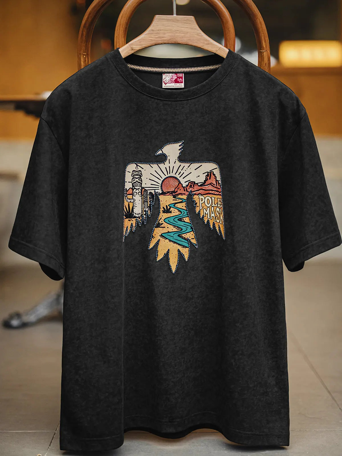 黒のコットンTシャツに刺繍とモニュメントバレー風プリントで雷鳥モチーフを大きくあしらったデザイン