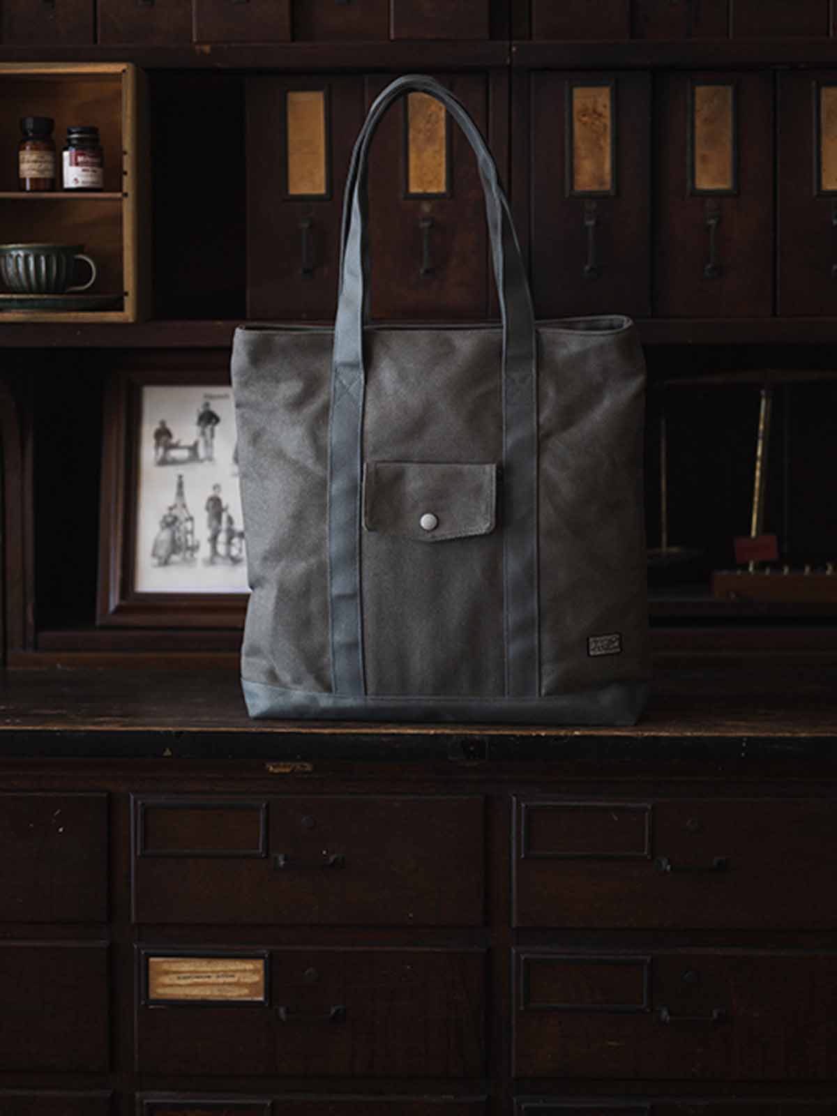 オリーブグリーン24オンスキャンバスのTalonジップ付きヴィンテージトートバッグ、前面フラップポケットと長めの肩紐の詳細。