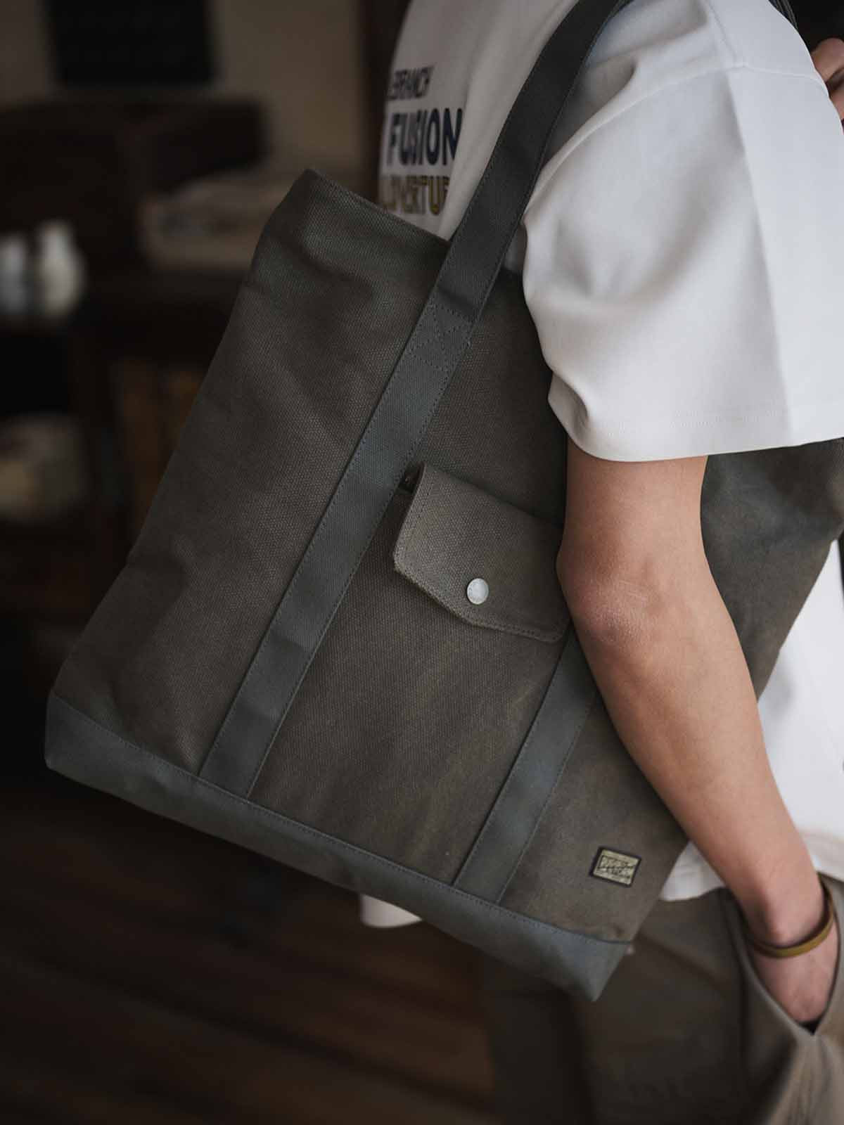 オリーブグリーン24オンスキャンバスのTalonジップ付きヴィンテージトートバッグ、前面フラップポケットと長めの肩紐の詳細。