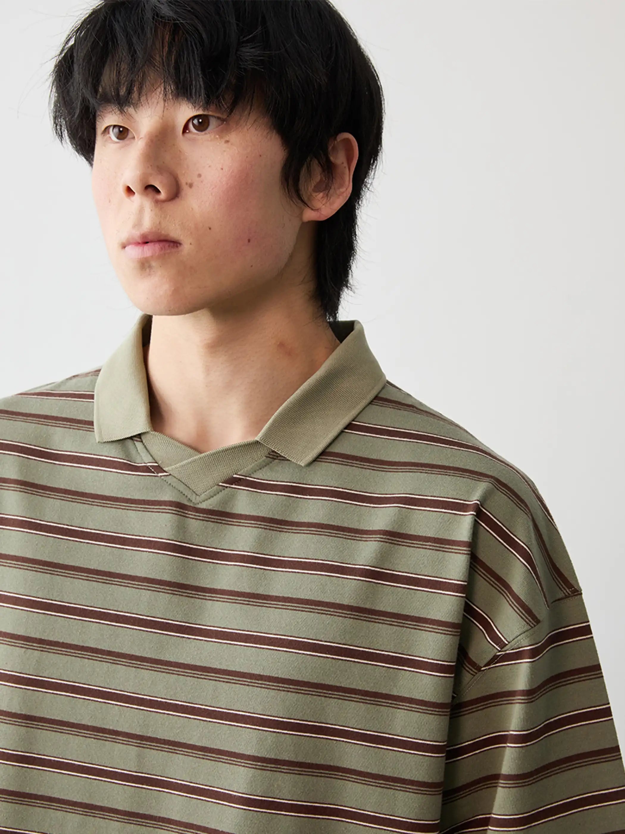モノトーンのストライプ柄が目を引くポロシャツ、フラットカラーとサイドスリットが特徴的