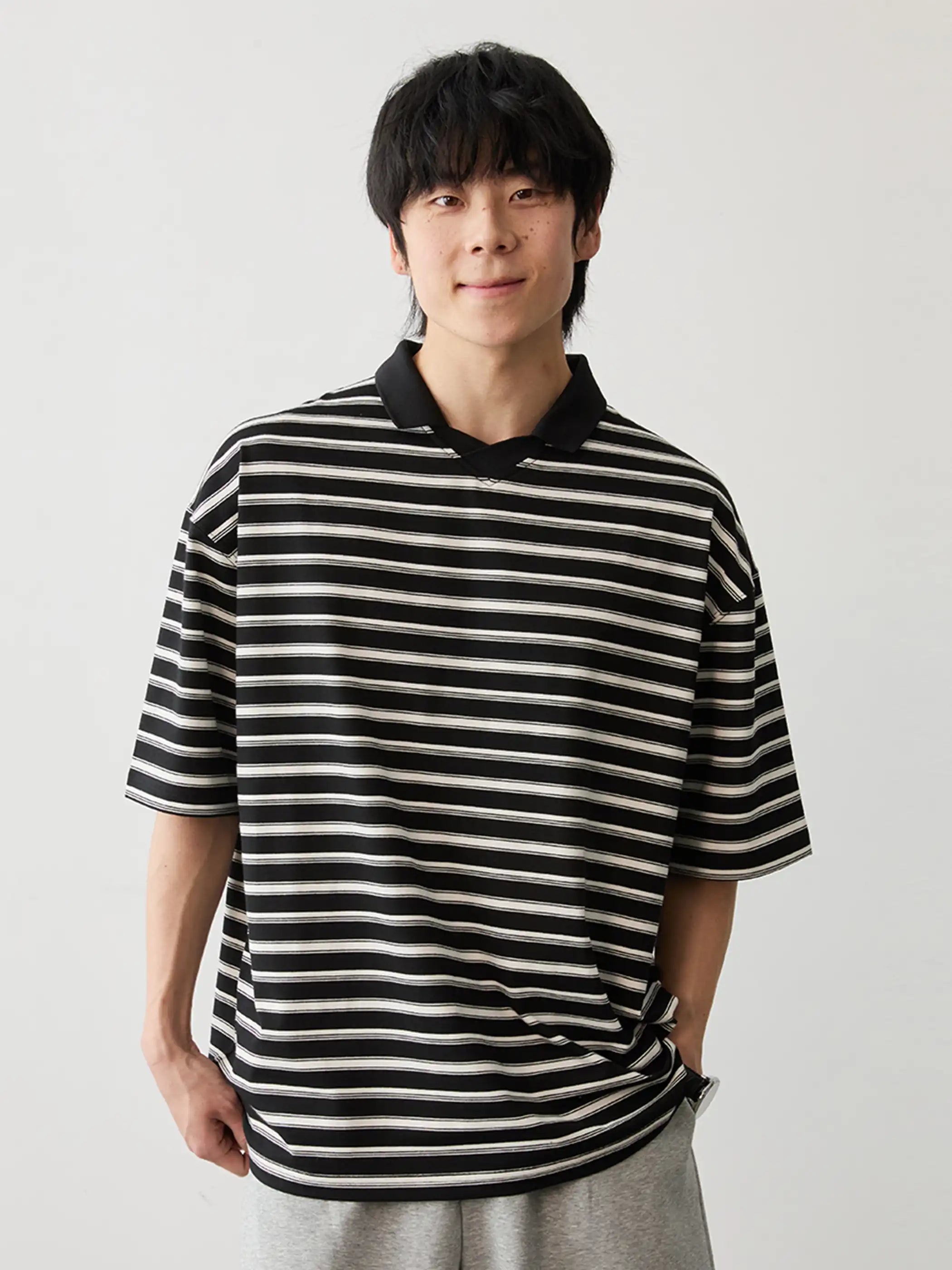 モノトーンのストライプ柄が目を引くポロシャツ、フラットカラーとサイドスリットが特徴的