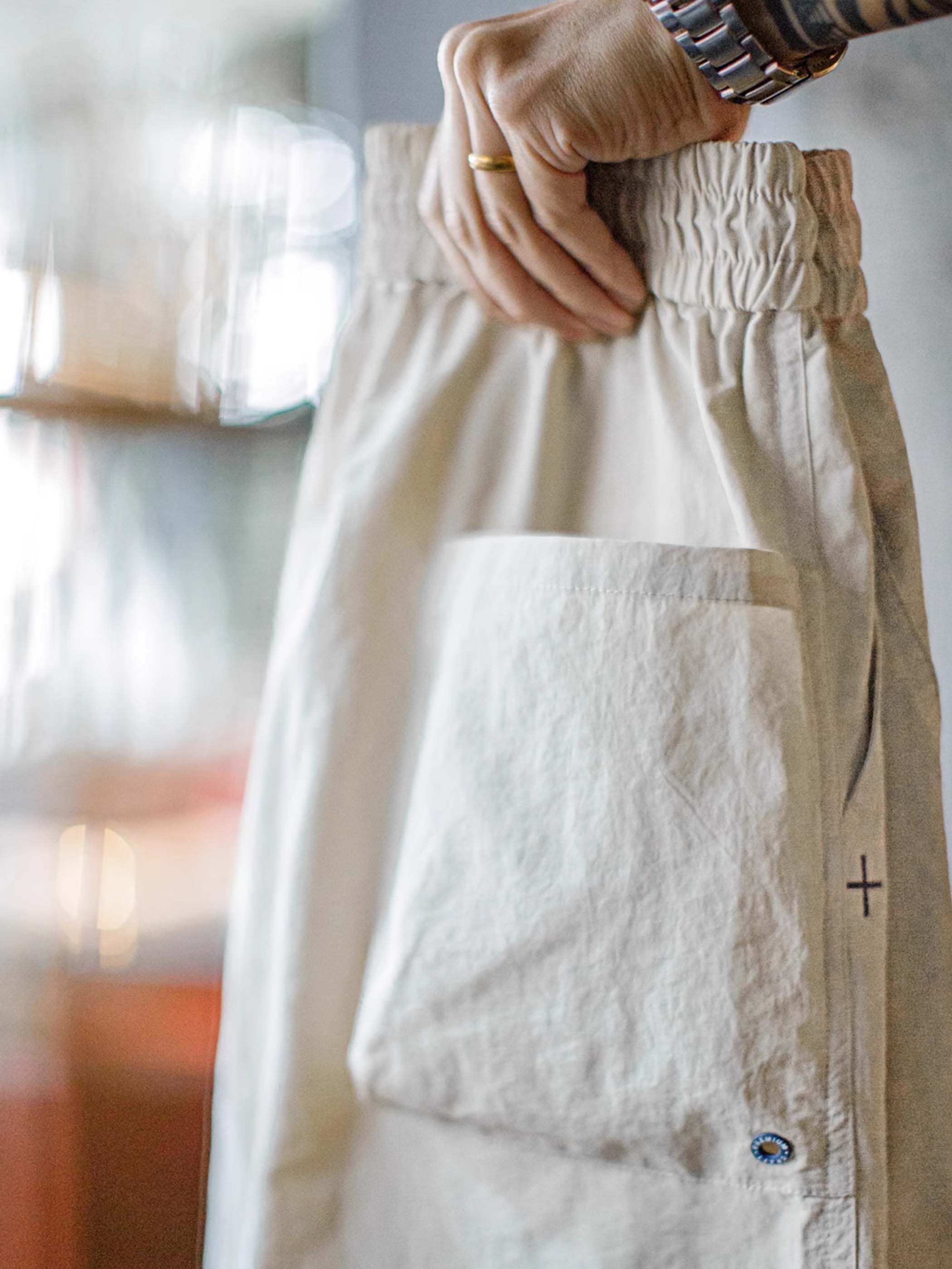 詳細画像: 膝のタックデザインと裾ドローコードのディテール特写