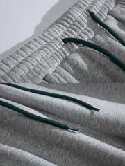 製品画像: 4色展開 カジュアル スウェットパンツ。裏起毛素材とルーズフィットデザインを採用した、冬に最適な厚手スウェットパンツの正面全体展示図。
詳細画像: 柔らかい裏起毛素材の質感と、冷気を防ぐ裾のリブデザインのディテールクローズアップ。