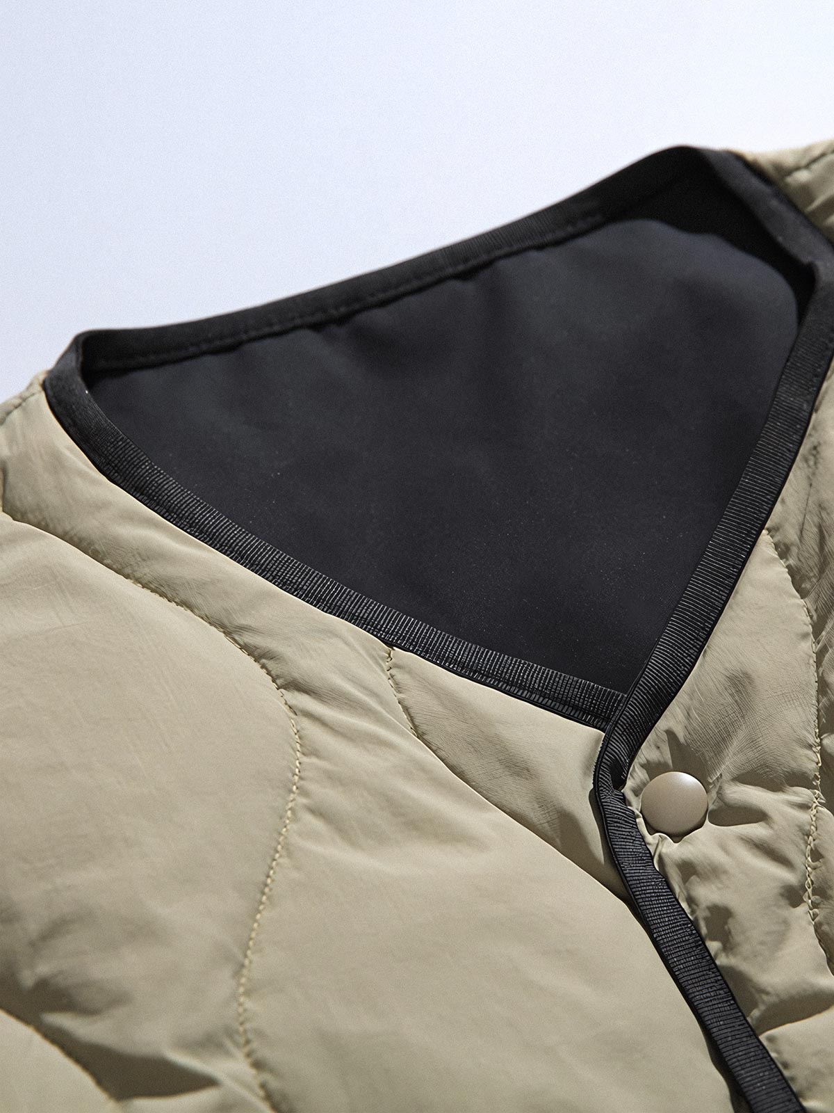 製品画像
「リバーシブル波形キルティングVネックダウン全体像。90%ホワイトダックダウン採用、カーキ、ブラック、アーミーグリーンの3色展開で実用性とスタイルを両立」
詳細画像
「リバーシブル波形キルティングダウンのポケットとキルティング加工のディテールクローズアップ。羽毛が均一に分布する設計」