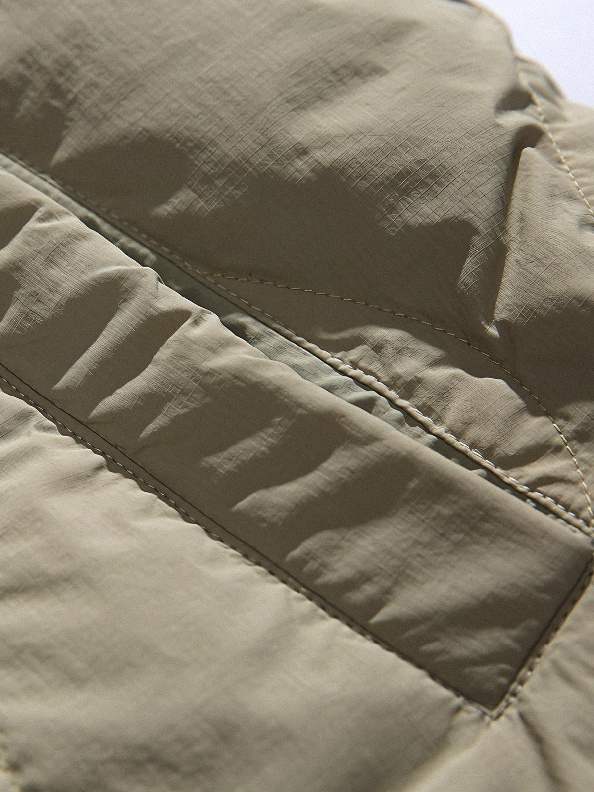 製品画像
「リバーシブル波形キルティングVネックダウン全体像。90%ホワイトダックダウン採用、カーキ、ブラック、アーミーグリーンの3色展開で実用性とスタイルを両立」
詳細画像
「リバーシブル波形キルティングダウンのポケットとキルティング加工のディテールクローズアップ。羽毛が均一に分布する設計」