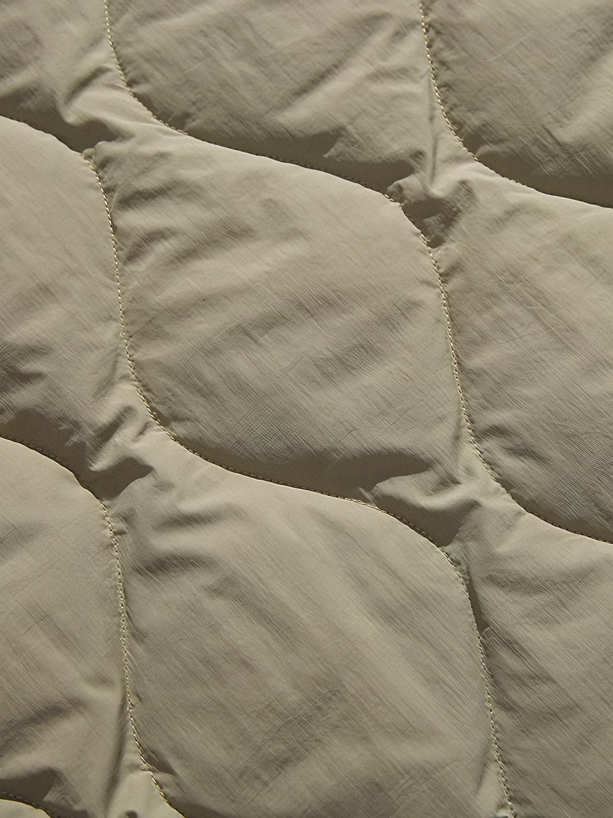 製品画像
「リバーシブル波形キルティングVネックダウン全体像。90%ホワイトダックダウン採用、カーキ、ブラック、アーミーグリーンの3色展開で実用性とスタイルを両立」
詳細画像
「リバーシブル波形キルティングダウンのポケットとキルティング加工のディテールクローズアップ。羽毛が均一に分布する設計」