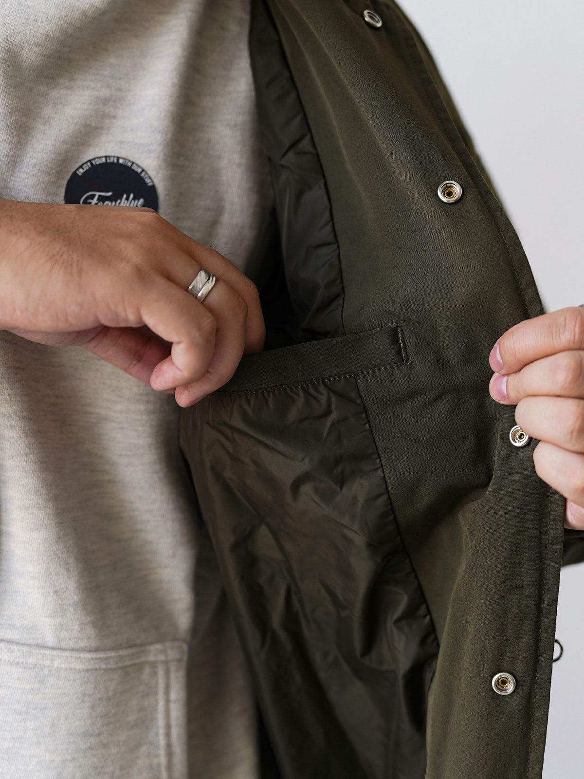 詳細画像
「胸元のロゴ刺繍とアシンメトリーな多機能ポケットのディテール特写。YKKカスタムジッパーとロゴ入りスナップボタンが、高品質のディテールを引き立て、機能性とスタイルを両立させています。ダブルレイヤーのリブ編みが施され、袖口と裾のフィット感と耐久性を向上させています。」
モデル画像
「モデルがアシンメトリーデザインの多ポケットキャンプワークジャケットを着用し、アウトドアシーンでのコーディネートを披露。ショート丈のルーズフィットシルエットが、カジュアルな日常コーディネートやアウトドア活動に最適なスタイルを提供します。」