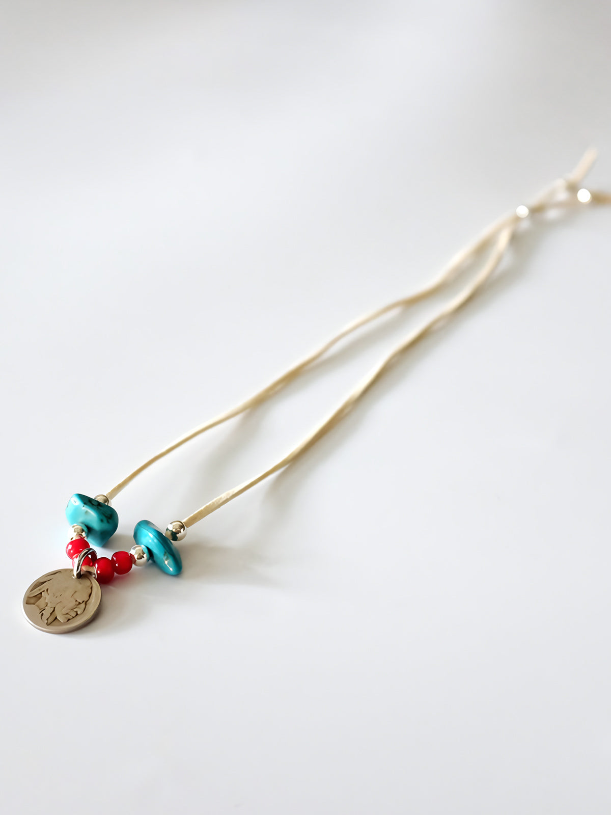 製品画像
「ハンドメイドインディアンコインネックレスの全体展示図。天然ターコイズ、アンティークガラスビーズ、アメリカの5セント硬貨を組み合わせたヴィンテージ感漂うデザインが特徴。」
詳細画像
「天然ターコイズとアンティークガラスビーズのディテール特写。各ビーズと硬貨が手作りで、個性あふれる美しさを際立たせています。」