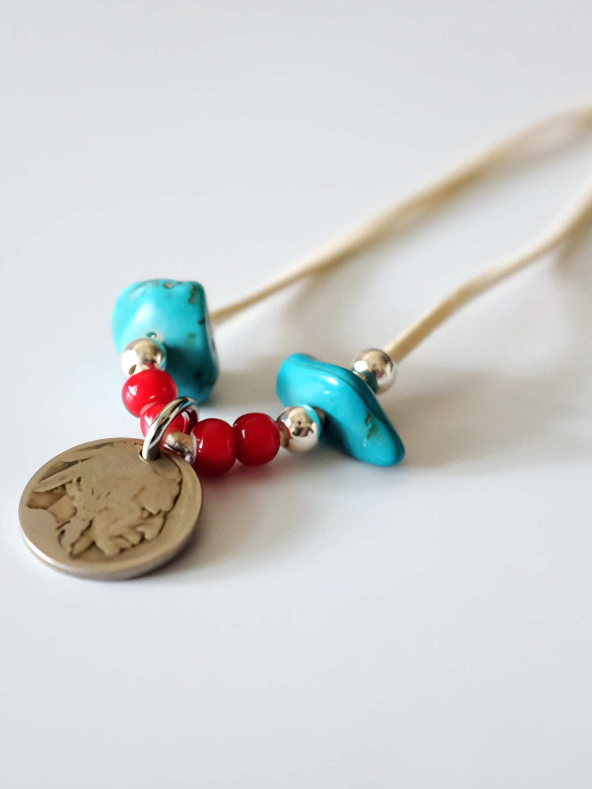製品画像
「ハンドメイドインディアンコインネックレスの全体展示図。天然ターコイズ、アンティークガラスビーズ、アメリカの5セント硬貨を組み合わせたヴィンテージ感漂うデザインが特徴。」
詳細画像
「天然ターコイズとアンティークガラスビーズのディテール特写。各ビーズと硬貨が手作りで、個性あふれる美しさを際立たせています。」