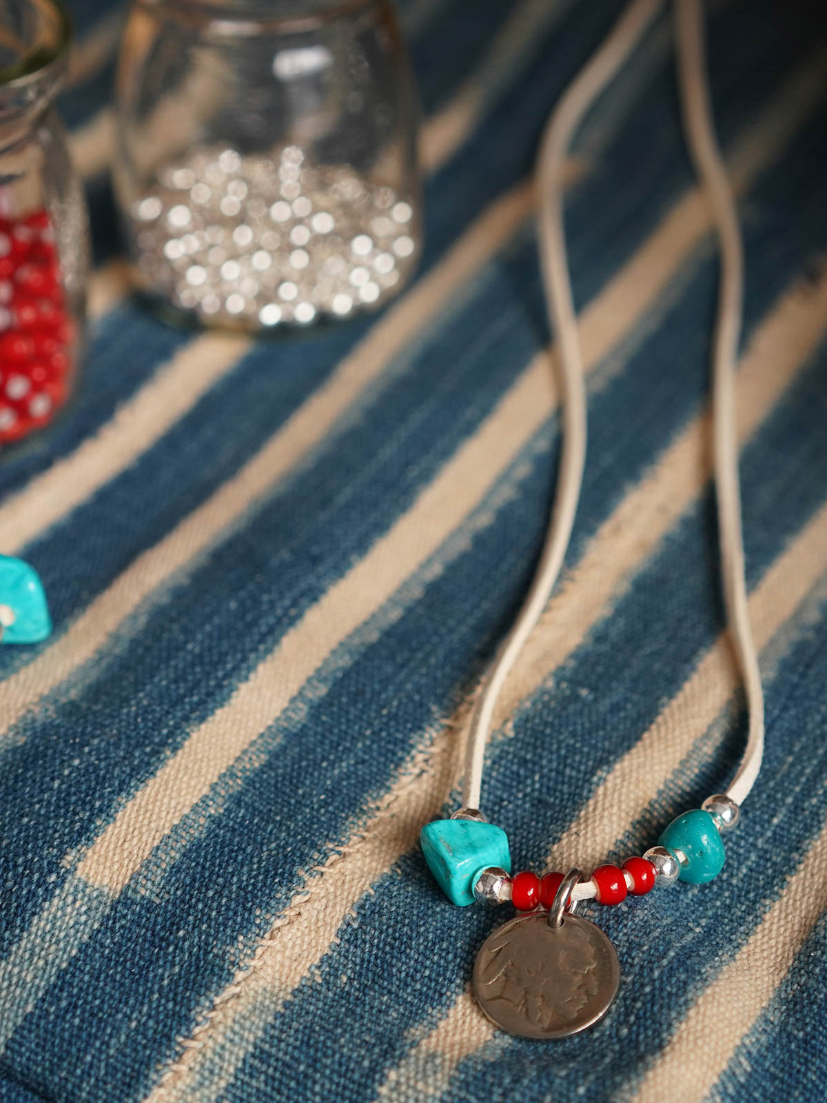 製品画像
「ハンドメイドインディアンコインネックレスの全体展示図。天然ターコイズ、アンティークガラスビーズ、アメリカの5セント硬貨を組み合わせたヴィンテージ感漂うデザインが特徴。」
詳細画像
「天然ターコイズとアンティークガラスビーズのディテール特写。各ビーズと硬貨が手作りで、個性あふれる美しさを際立たせています。」