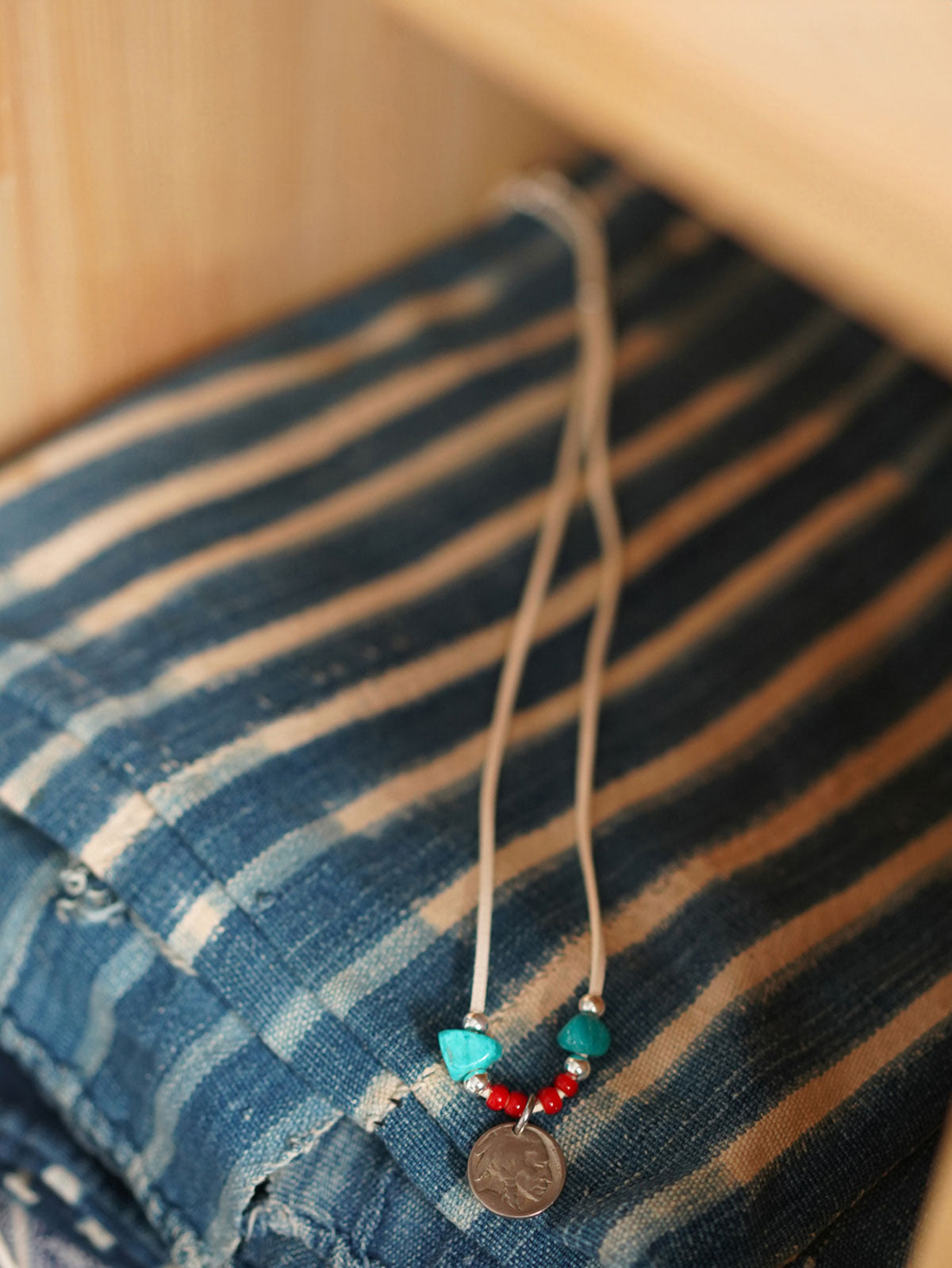 製品画像
「ハンドメイドインディアンコインネックレスの全体展示図。天然ターコイズ、アンティークガラスビーズ、アメリカの5セント硬貨を組み合わせたヴィンテージ感漂うデザインが特徴。」
詳細画像
「天然ターコイズとアンティークガラスビーズのディテール特写。各ビーズと硬貨が手作りで、個性あふれる美しさを際立たせています。」