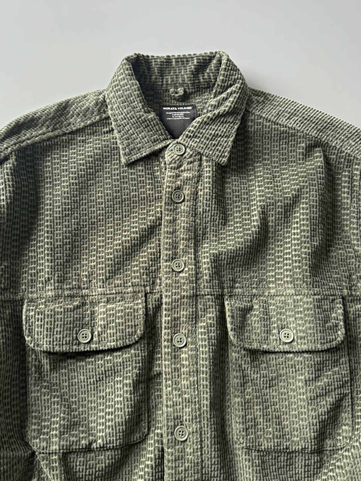 製品画像
「コーデュロイウォッシュ加工ヴィンテージ長袖シャツ全体の展示図。ウォッシュ加工によるヴィンテージ感とコーデュロイ素材が融合し、テクスチャーの美しさが引き立つデザイン。」
詳細画像
「胸元のフラップポケットとウォッシュ加工による質感ディテール特写。コーデュロイ素材が重厚感と柔らかさを兼ね備え、ヴィンテージ感を強調。」