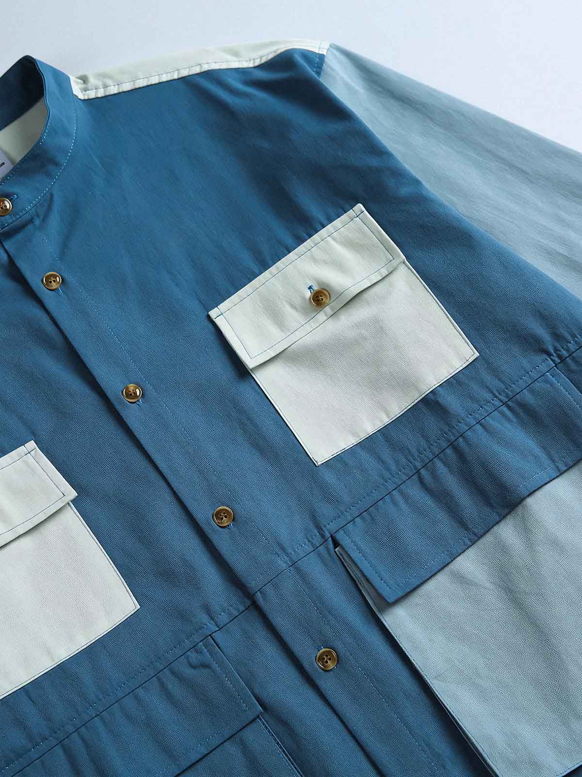 製品画像
カラーブロックデザインと小さなスタンドカラーが融合したワークシャツ、クラシックなワークウェアスタイルに現代的な感覚を加えたデザイン。柔らかく快適な素材で、1日中着用するのに適しています。
詳細画像
ユニークなカラーブロック要素と多ポケットデザインが特徴のワークシャツ。胸元の2つのカラーブロックポケットと裾の2つの大きなポケットが機能性とレイヤード感を引き立て、収納力も抜群です。小さなスタンドカラーがディテールにアクセントを加えています。