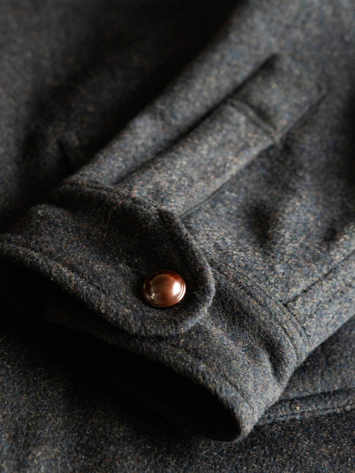 コートのディテールショット、ビンテージボタンとツイード生地の細部を展示