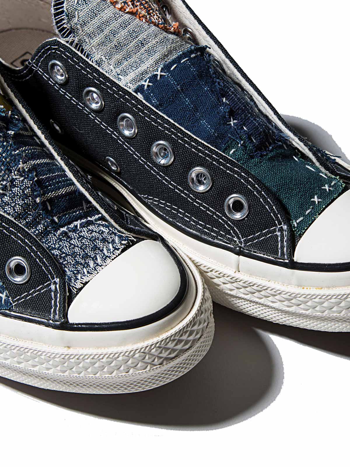 製品画像: 植物染め古布手作り刺し子パッチワーク1970Sローカットキャンバスシューズの正面画像。手工芸とヴィンテージデザインの融合が特徴的。
詳細画像: 刺し子と侗族(ドン族)の手織り布のディテール特写。伝統技術の細部が見える画像。