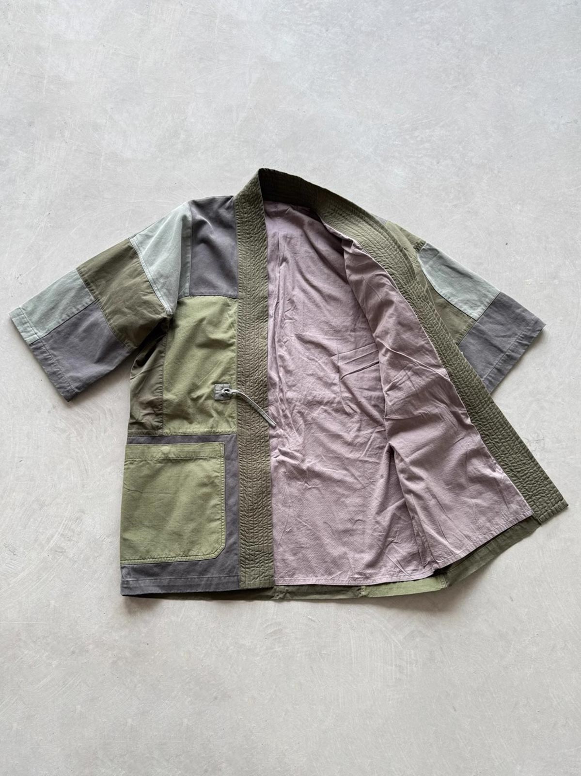 製品画像: ヴィンテージウォッシュ加工のパッチワーク生地を使用した五分袖ハンテンの正面画像。色のコントラストデザインとヴィンテージスタイルが鮮明に表示され、レトロな風合いが強調されています。
詳細画像: YKK真鍮ジッパーと真皮ディテールのクローズアップ。重工水洗加工による独自のビンテージ感が詳しく見える特写画像。