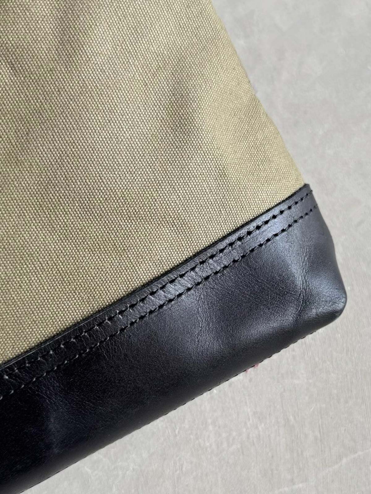 製品画像: 頭層牛革とウォッシュキャンバスのショルダーバッグ、正面から見た全体像。レトロなデザインと高品質な素材が際立つ。
詳細画像: 頭層牛革のショルダーバッグの金属ハードウェアと純銅YKKファスナーの詳細特写。本革引き手の質感と精密な仕上げが強調されている。