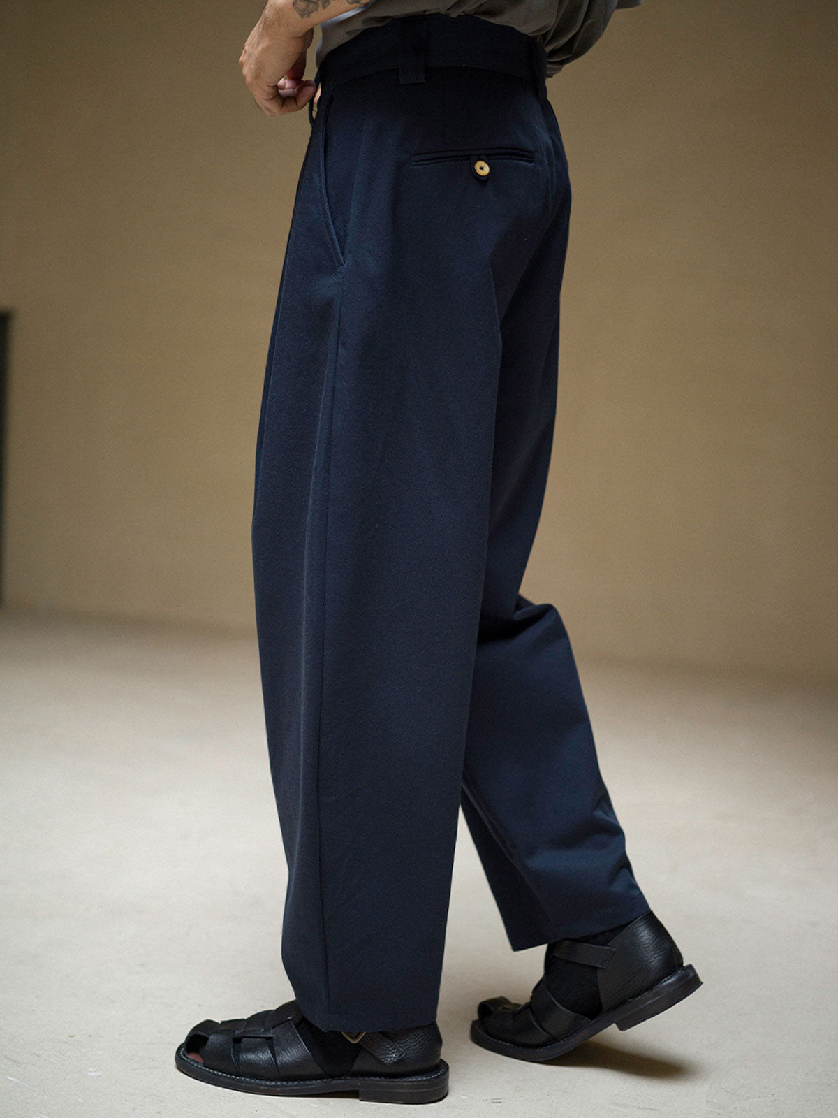 詳細画像: ツイル素材のディテールとプリーツが特徴のパンツ、シンプルなデザインで幅広いシーンに対応
モデル画像: モデルが着用する立体裁断シングルプリーツパンツ、テーパードデザインで美しいシルエットを演出