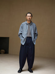 詳細画像: ツイル素材のディテールとプリーツが特徴のパンツ、シンプルなデザインで幅広いシーンに対応
モデル画像: モデルが着用する立体裁断シングルプリーツパンツ、テーパードデザインで美しいシルエットを演出