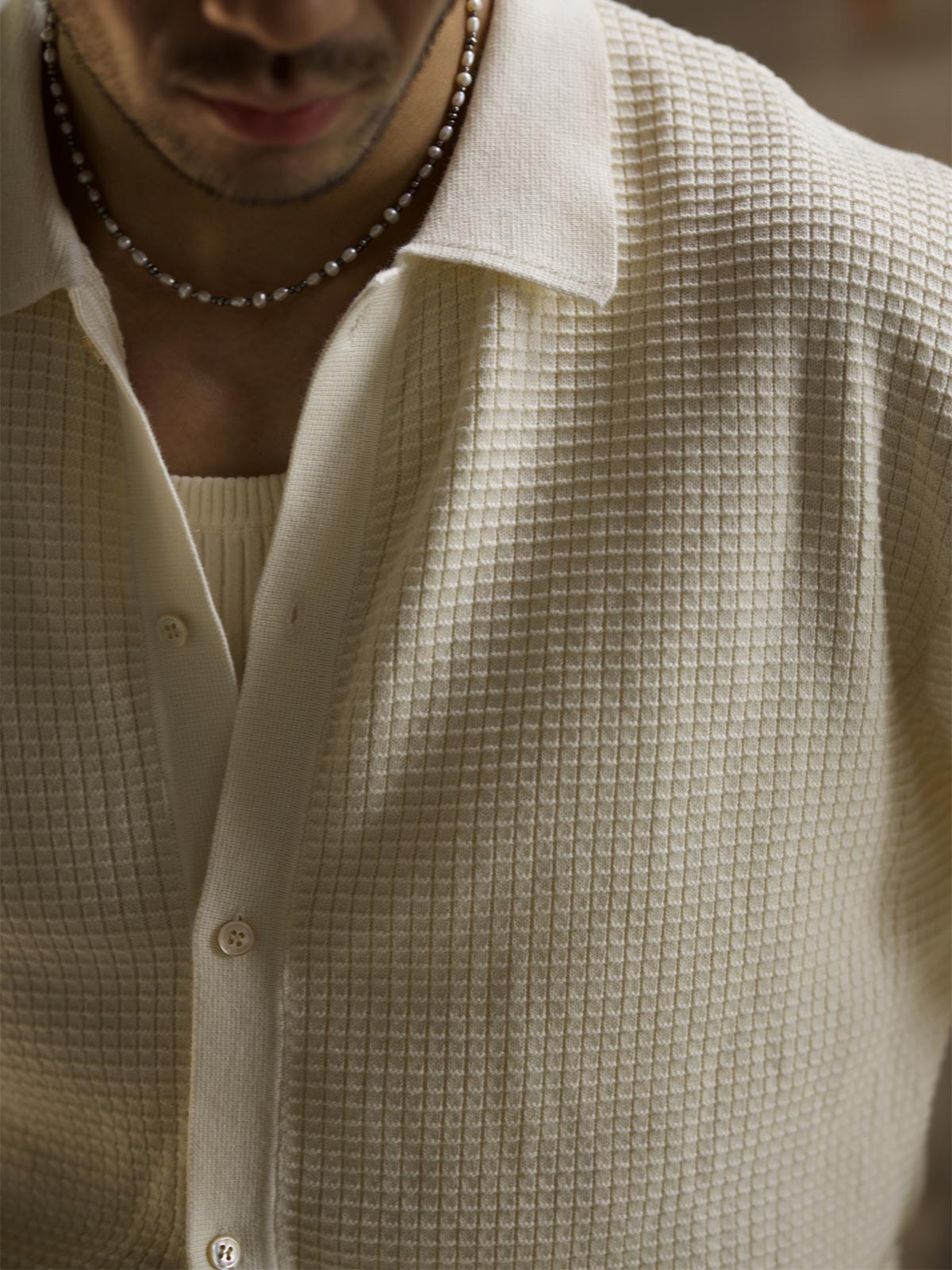 詳細画像: ワッフル編みのテクスチャとキューバシャツ風襟のディテールをクローズアップ
モデル画像: 男性モデルが着用するキューバシャツ風ニットシャツ - 全体スタイルと着こなし例