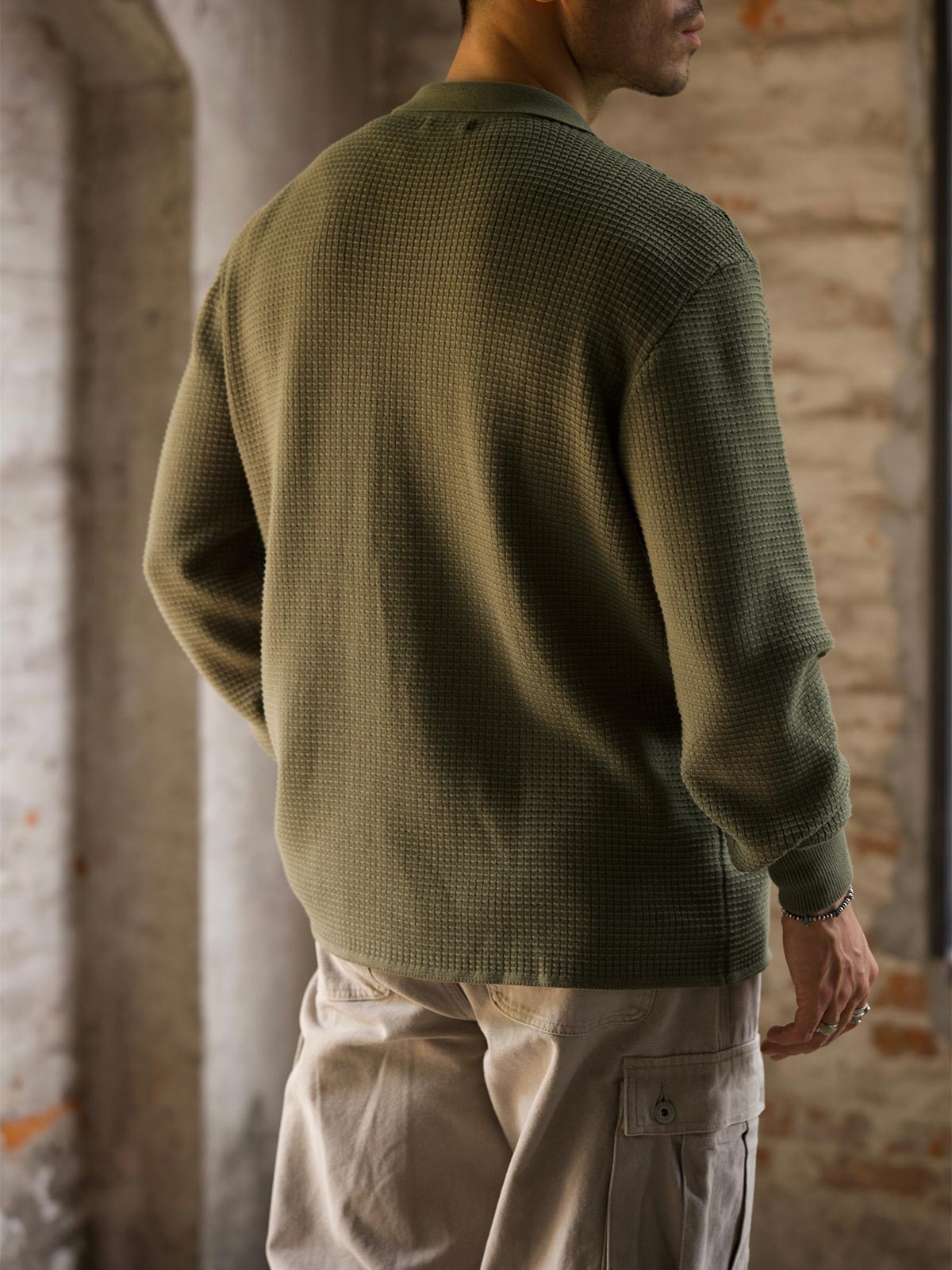 詳細画像: ワッフル編みのテクスチャとキューバシャツ風襟のディテールをクローズアップ
モデル画像: 男性モデルが着用するキューバシャツ風ニットシャツ - 全体スタイルと着こなし例