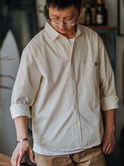 詳細画像: 細ストライプとダブルボタンカフスのディテール
モデル画像: 細ストライプのゆったりシルエットシャツを着用した男性