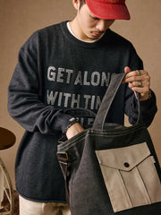 詳細画像: 透かし刺繍ロゴとナチュラルロールドヘムのディテール特写、細部の精巧さを強調
モデル画像: モデル着用のマスタードイエローの透かしロゴ刺繍セーター、ヴィンテージカジュアルなコーディネート例