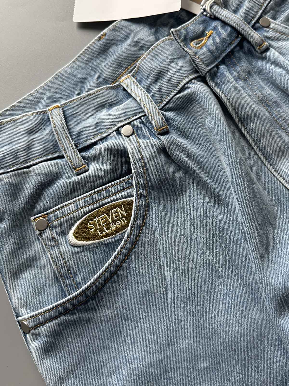 製品画像: 刺繍デザインが特徴のテーパードシルエットデニムパンツ全体画像
詳細画像: ポケット部分の刺繍ディテールとクラシックデニムブルーの生地