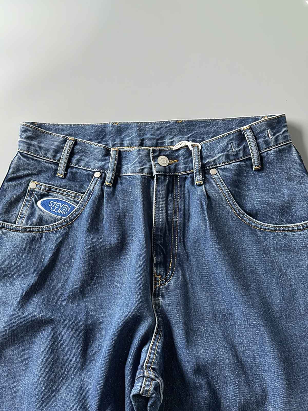 製品画像: 刺繍デザインが特徴のテーパードシルエットデニムパンツ全体画像
詳細画像: ポケット部分の刺繍ディテールとクラシックデニムブルーの生地