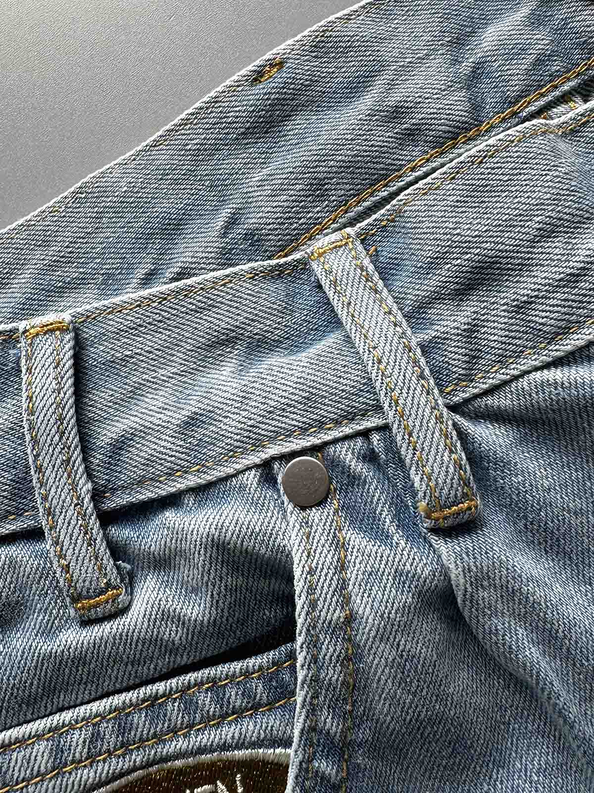 製品画像: 刺繍デザインが特徴のテーパードシルエットデニムパンツ全体画像
詳細画像: ポケット部分の刺繍ディテールとクラシックデニムブルーの生地