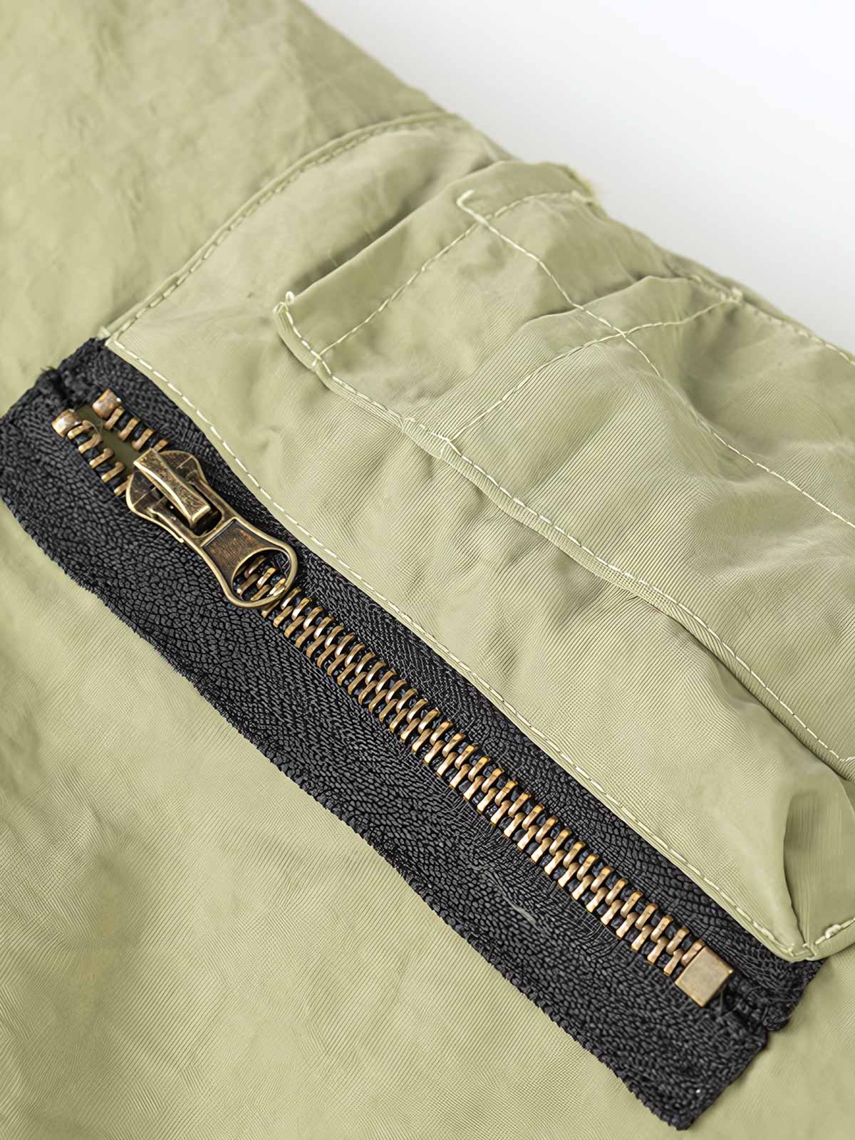 製品画像:ヴィンテージ風リバーシブルミリタリーフライトジャケットの正面展示。ミリタリースタイルに最適なリバーシブルデザインのジャケット。
詳細画像:刺繍ディテールと多機能ポケット、ジッパーのクローズアップ。保温性とデザイン性を両立するディテール。