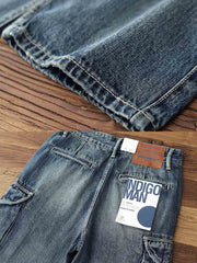 製品画像: レトロウォッシュ加工のヘビーウェイトデニムワークパンツのフロントビュー
詳細画像: サイドポケットとレザー調整バックルのディテール特写