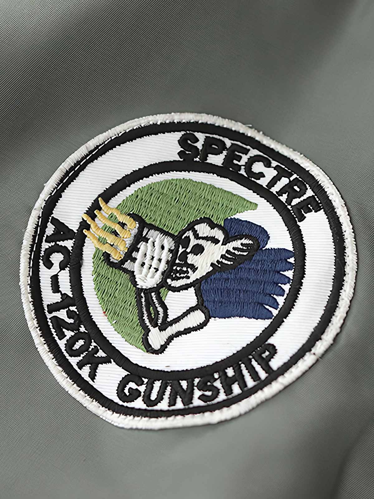 製品画像:ヴィンテージMA-1フライトジャケットの正面図。防水ナイロン素材とオレンジ色の裏地、刺繍バッジが特徴的なデザイン。
詳細画像:刺繍バッジと識別テープ、ジッパーのディテールをクローズアップした画像。ミリタリーウェアの本格的なスタイルを強調。