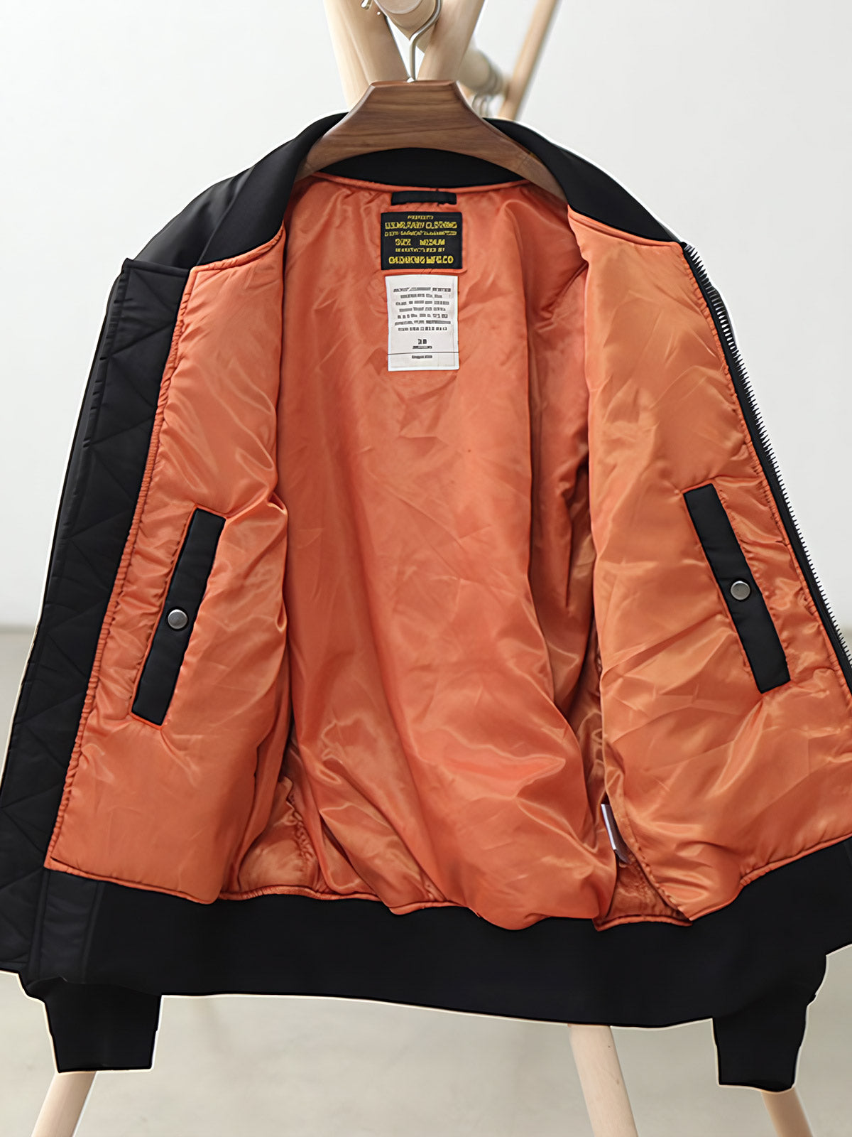 製品画像:ヴィンテージMA-1フライトジャケットの正面図。防水ナイロン素材とオレンジ色の裏地、刺繍バッジが特徴的なデザイン。
詳細画像:刺繍バッジと識別テープ、ジッパーのディテールをクローズアップした画像。ミリタリーウェアの本格的なスタイルを強調。