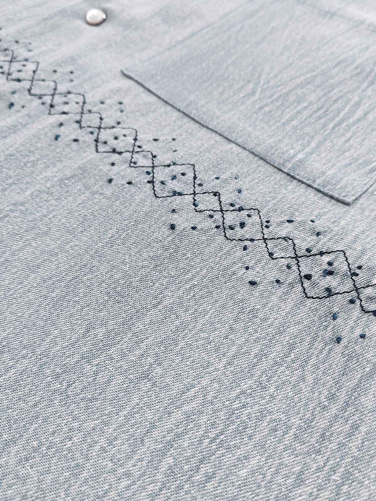 製品画像: ウォッシュ刺し子ストライプスタンドカラーデニムシャツ全体表示。東洋風デザインとモダンな刺し子刺繍が特徴のカジュアルシャツ。
詳細画像: ストライプ状の刺し子刺繍ディテール表示。民族風と幾何学模様が融合したデザインで、シャツのアクセントに。