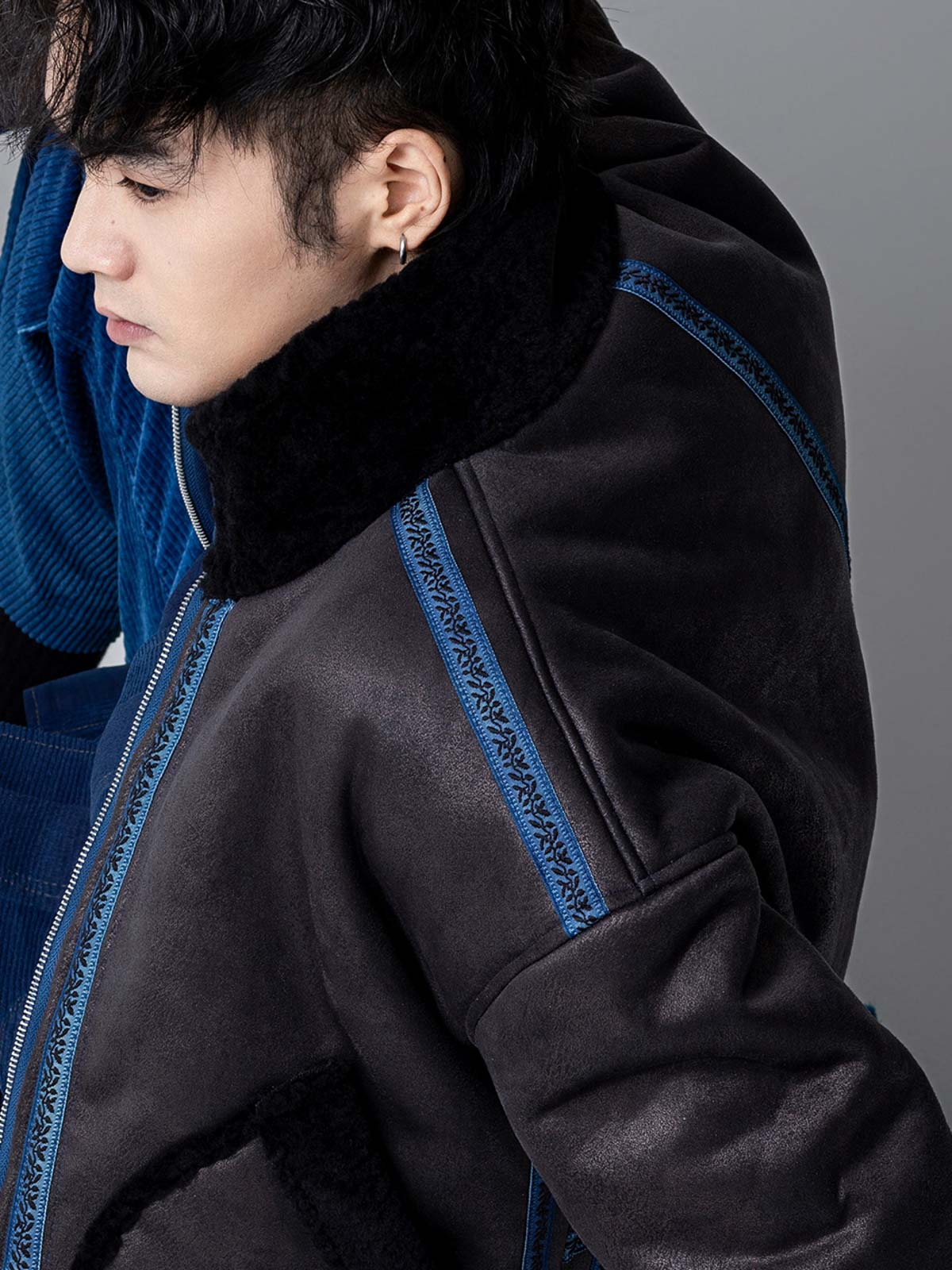 詳細画像: 草木模様のテープパッチワークディテール表示。ヴィンテージ感と高級感を兼ね備えたユニークな仕上がり。
モデル画像: モデル着用による厚手ムートンジャケットのシティスタイル。冬のカジュアルシーンに最適なアウター。