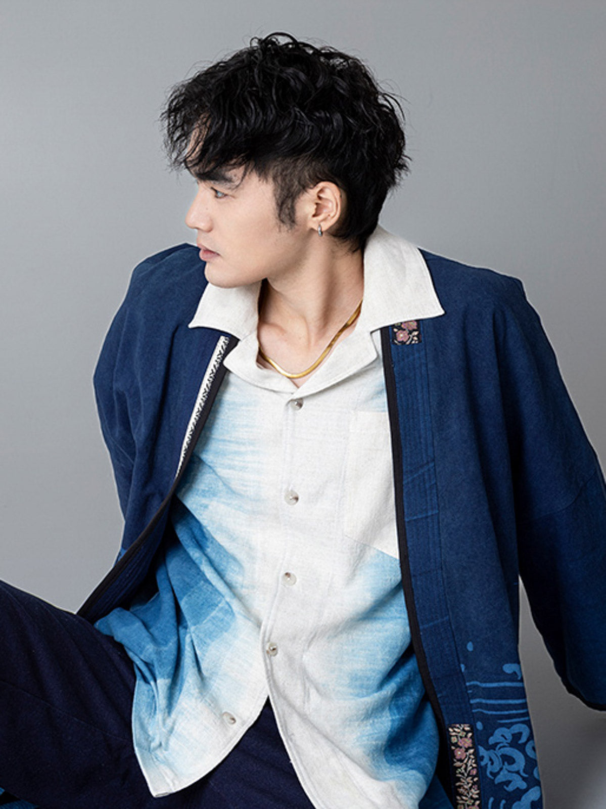 詳細画像:和柄の抜染と段落ち抜染のディテールをクローズアップ。刺し子刺繍と織り帯のディテールが、工芸的な価値を引き立てる。
モデル画像:モデルがリネンはんてんを着用。リネンパンツと合わせた品のあるカジュアルスタイルを提案。