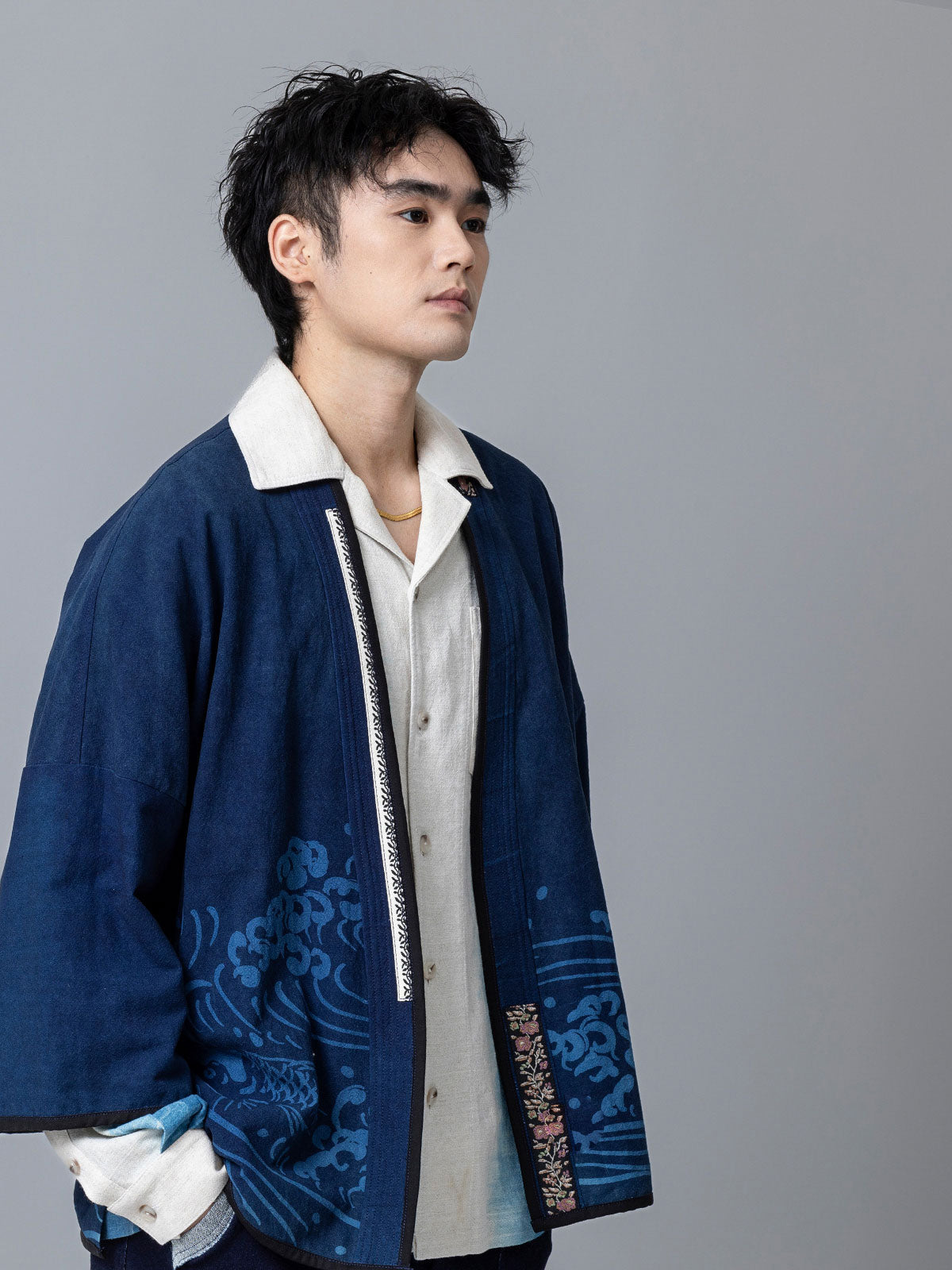 詳細画像:和柄の抜染と段落ち抜染のディテールをクローズアップ。刺し子刺繍と織り帯のディテールが、工芸的な価値を引き立てる。
モデル画像:モデルがリネンはんてんを着用。リネンパンツと合わせた品のあるカジュアルスタイルを提案。