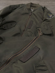 製品画像:ヴィンテージL-2フライトジャケットの正面展示。軽量ナイロン素材とリブディテールが特徴のクラシックなフライトジャケット。
詳細画像:酸素マスクホースクリップと真鍮製四合ボタンのディテールをクローズアップ。戦後の空軍スタイルを表現するディテール。