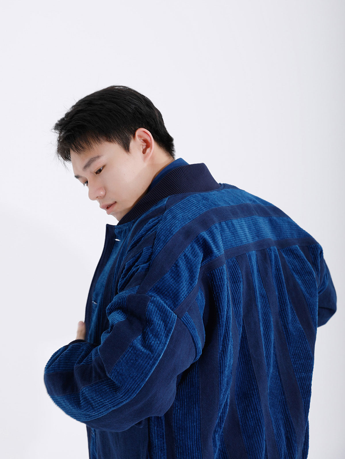 詳細画像: 藍染めストライプと多機能ポケットのディテール画像。ダイヤ柄キルティング加工の中綿が見える耐久性と保温性の高い仕上がり。
モデル画像: モデルが着用する藍染めとストライプパッチワークの民族風スタンドカラージャケット。スポーティーな袖口とゆったりとしたシルエットが映えるコーディネート。