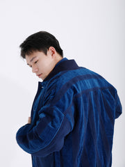 詳細画像: 藍染めストライプと多機能ポケットのディテール画像。ダイヤ柄キルティング加工の中綿が見える耐久性と保温性の高い仕上がり。
モデル画像: モデルが着用する藍染めとストライプパッチワークの民族風スタンドカラージャケット。スポーティーな袖口とゆったりとしたシルエットが映えるコーディネート。