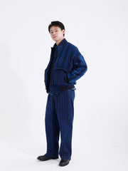 詳細画像: 藍染めストライプと多機能ポケットのディテール画像。ダイヤ柄キルティング加工の中綿が見える耐久性と保温性の高い仕上がり。
モデル画像: モデルが着用する藍染めとストライプパッチワークの民族風スタンドカラージャケット。スポーティーな袖口とゆったりとしたシルエットが映えるコーディネート。